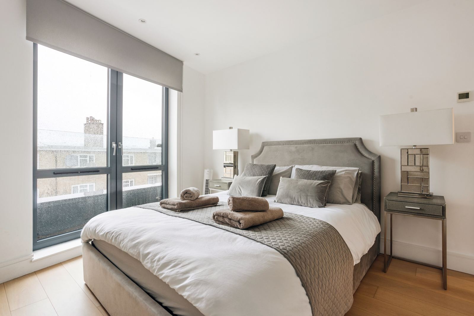 Bedroom with velvet headboard and mirrored lamps